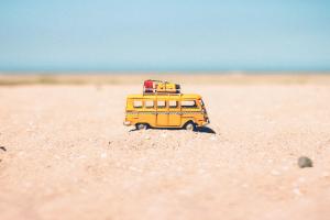 Gelber Bully mit Urlaubsgepäck im Sand mit Meer im Hintergrund