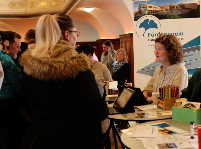 Lehrerin berät Eltern an einem Messestand