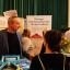 Schulleiter berät Eltern an einem Messestand.
