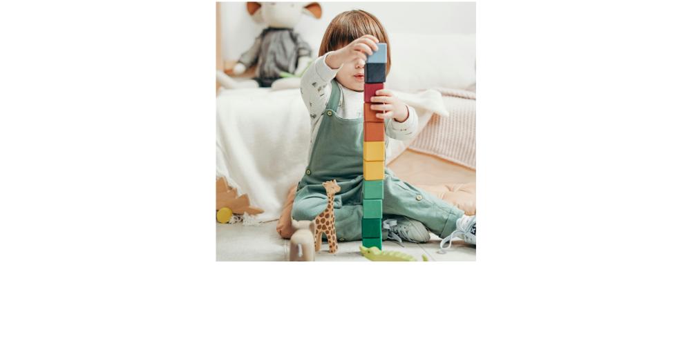 Kleines Kind spielt mit Spielzeugtieren und Bauklötzchenturm